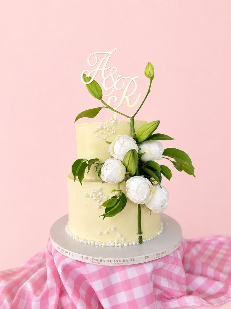 Custom two-tier engagement cake with gold A&R monogram, pearls and white peonies